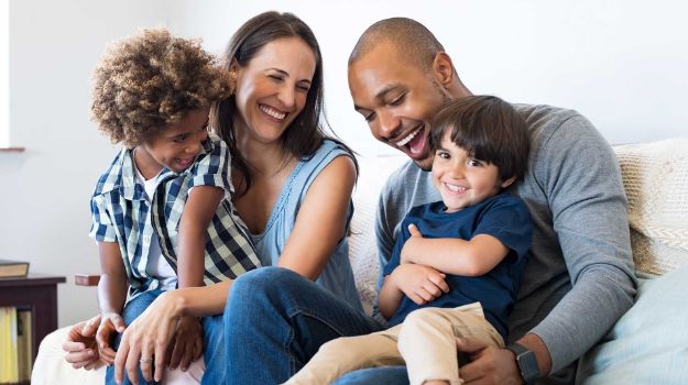 Happy multiethnic family sitting on sofa laughing together.